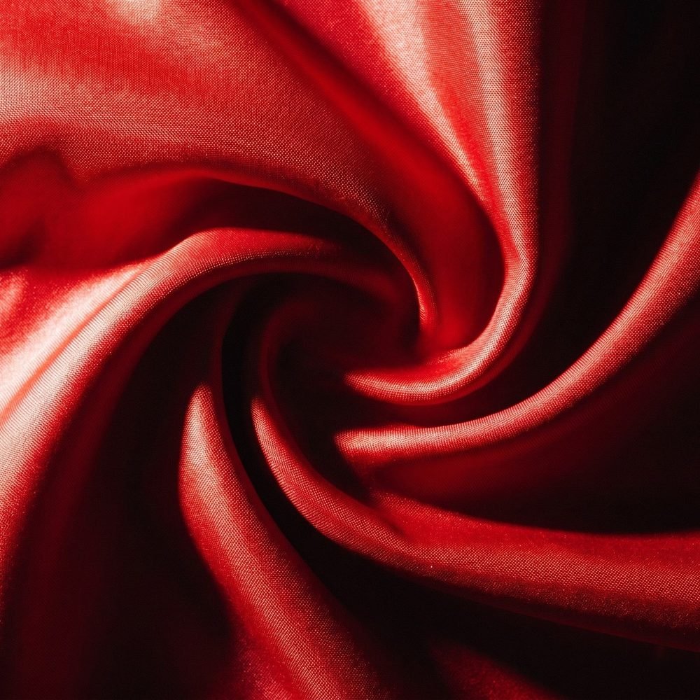 Scarlet silk twisted into a spiral of deep folds, highlights blazing along the crests