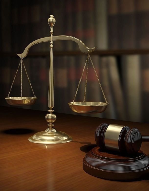 Brass scales of justice and a gavel on a desk, representing a Shantha Hi Tech law practice client