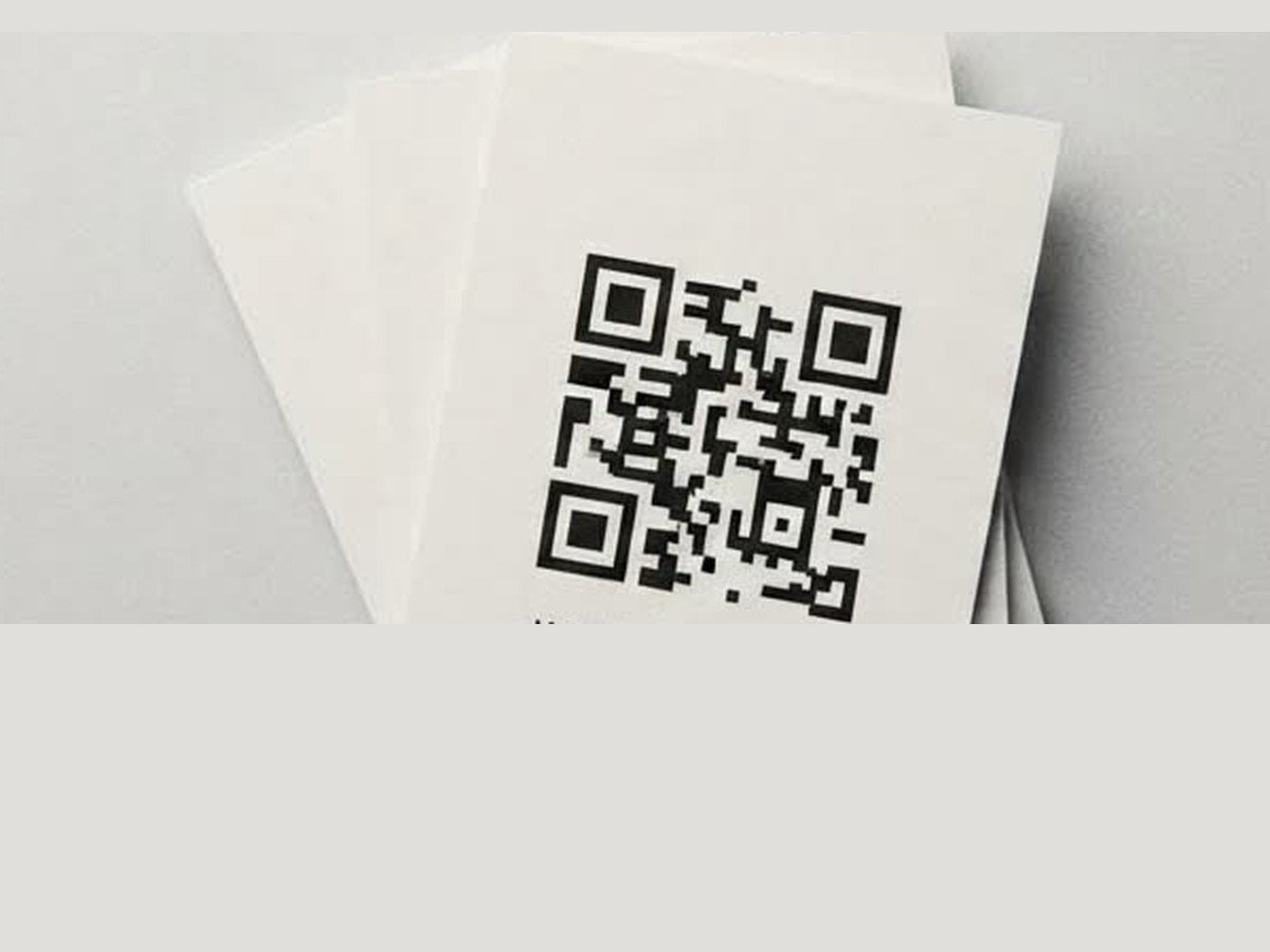 A small stack of printed cards with a QR code on top, on a grey surface