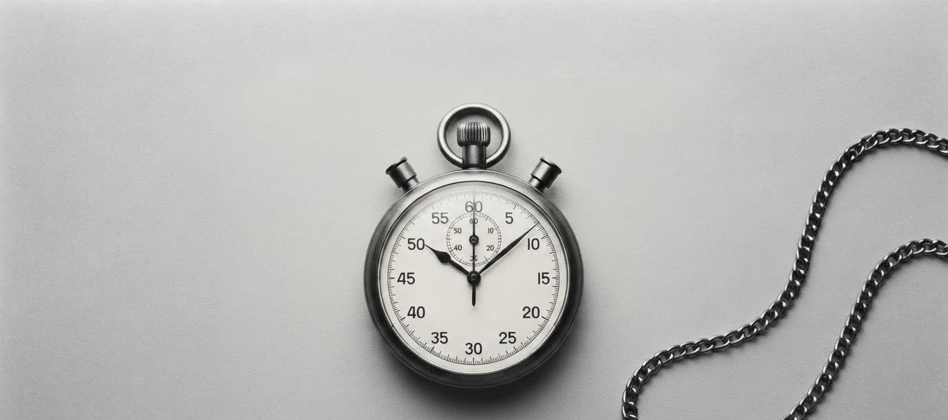 A stopwatch and its chain resting on a grey surface