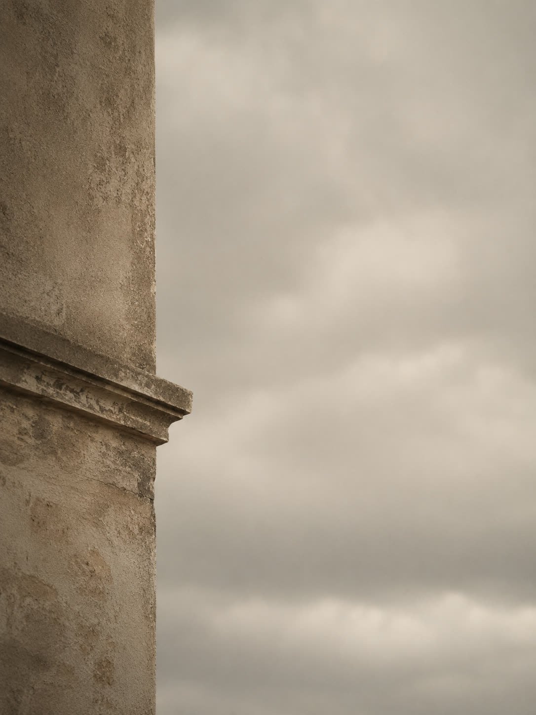 A weathered stone cornice against an overcast sky